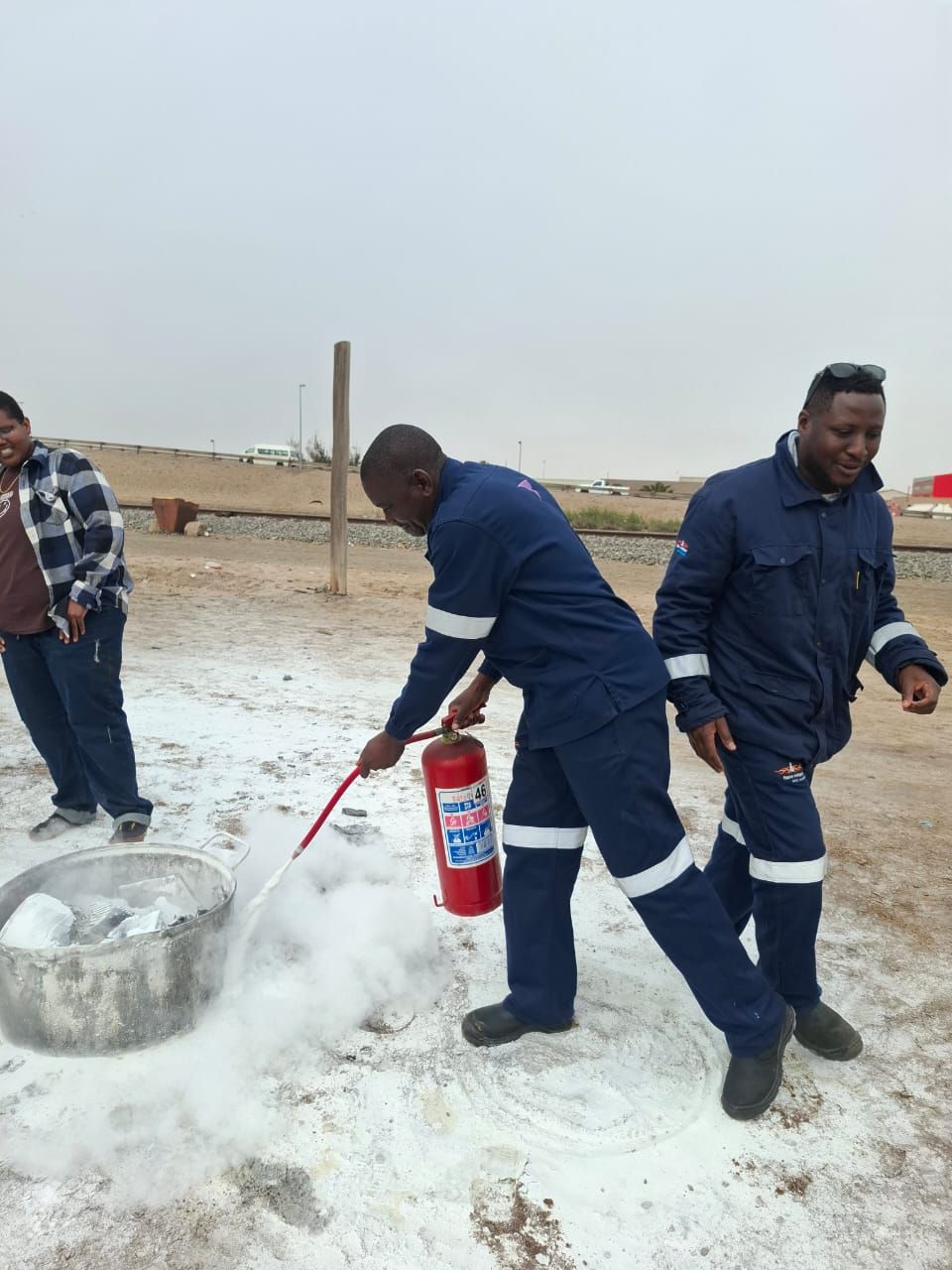 Trainee operating fire extinguisher on site