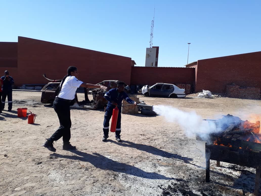 Instructor guiding a trainee during live extinguisher drill